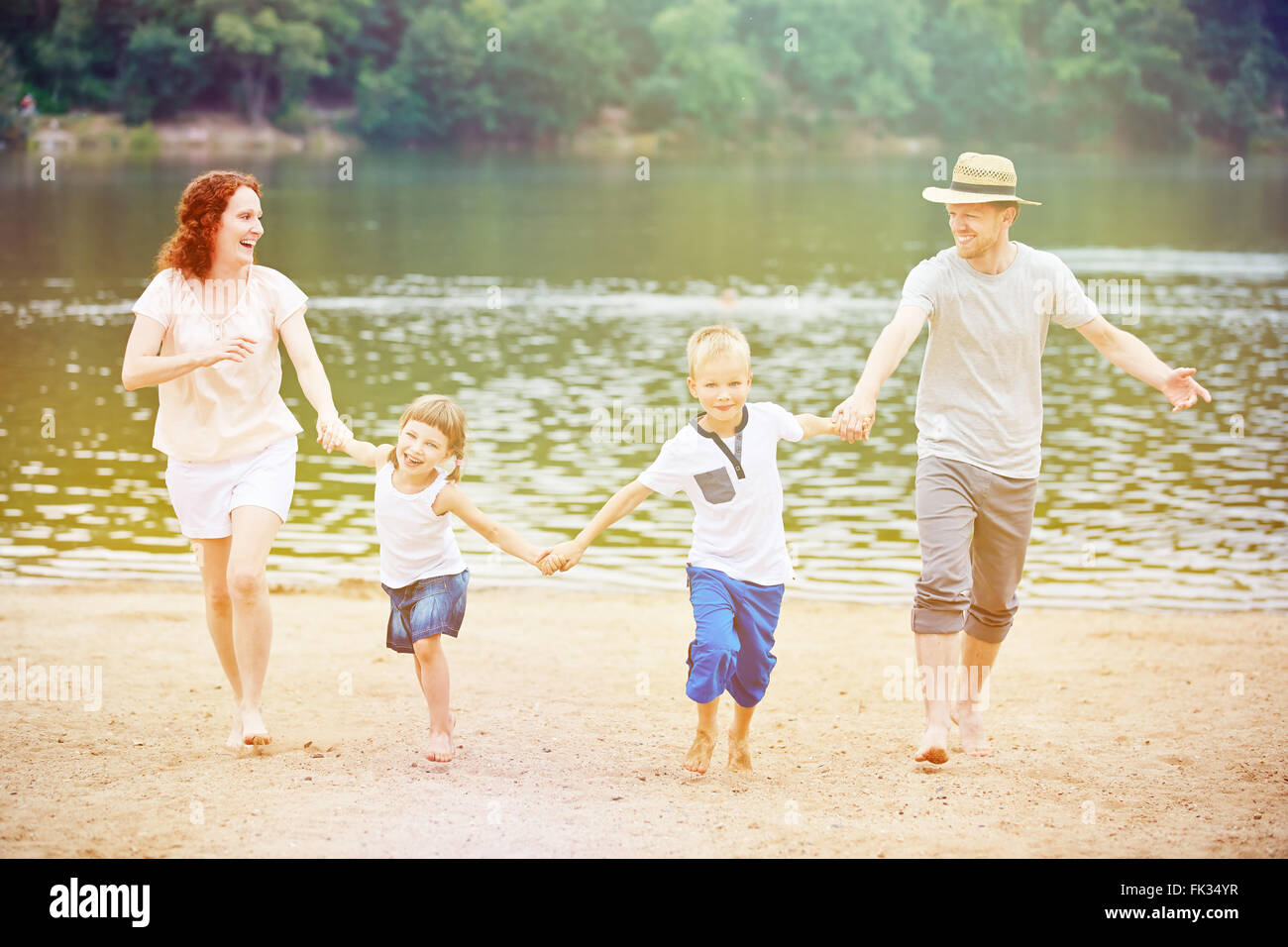 Happy family with children having summer vacation at lake with beach