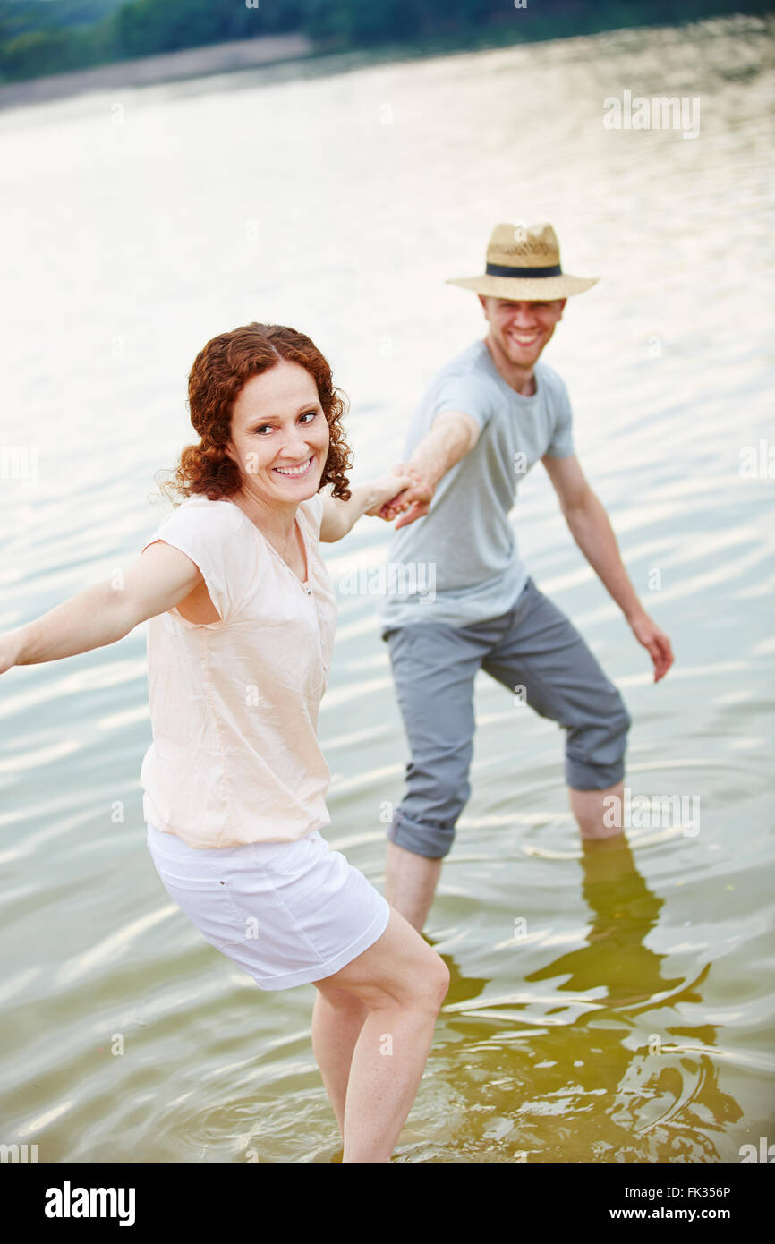 Laughing young couple playing in water of lake in summer Stock Photo