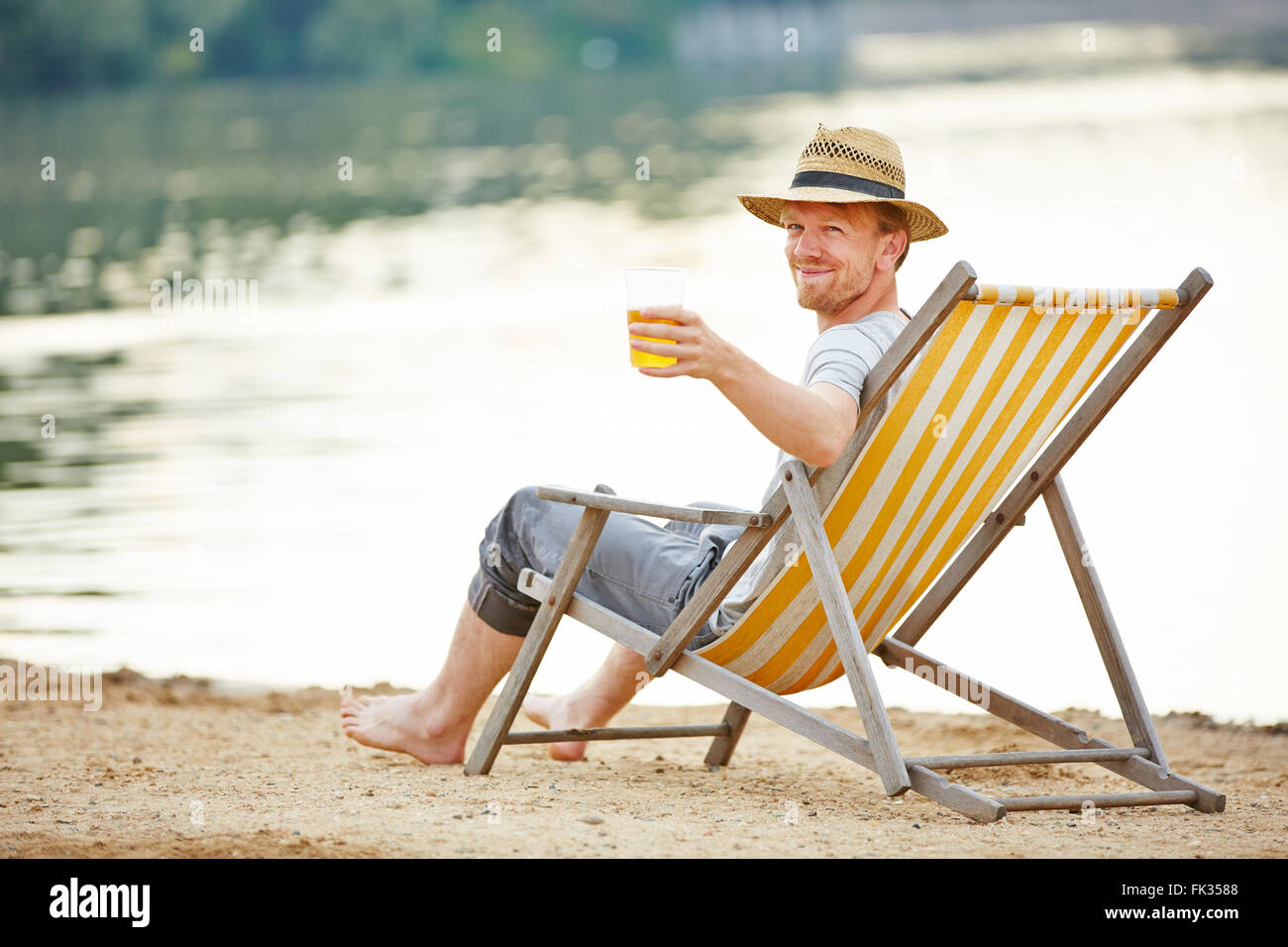 Relaxed man drinking beer in deck chair in summer Stock Photo 97800312