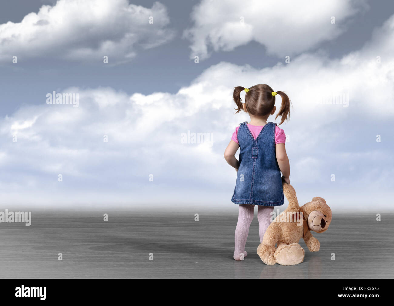 Child girl with toy bear looking into the distance, back view, perception concept Stock Photo