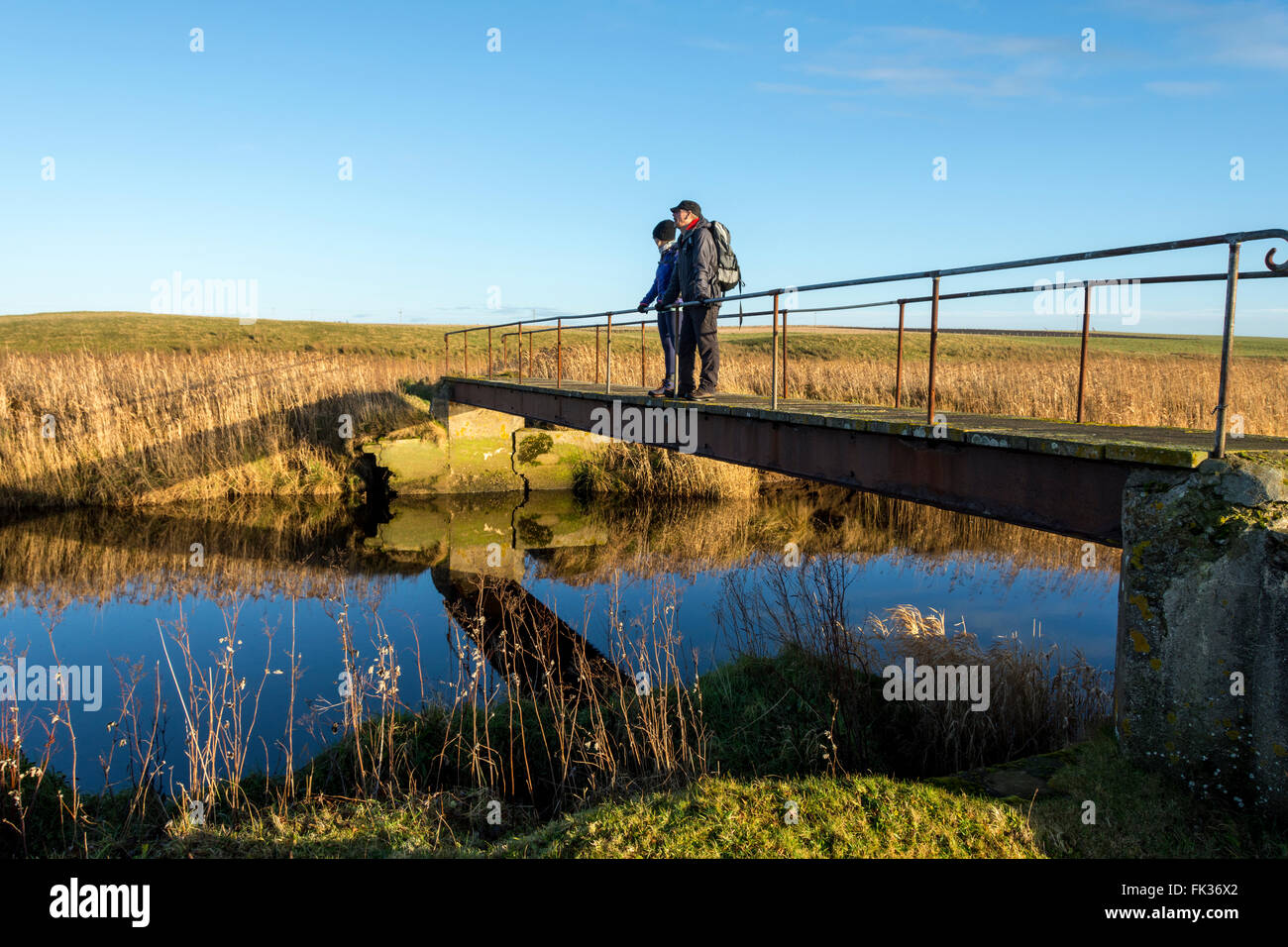 Two walkers on a footbridge over the Wick River, near Wick, Caithness, Scotland, UK Stock Photo