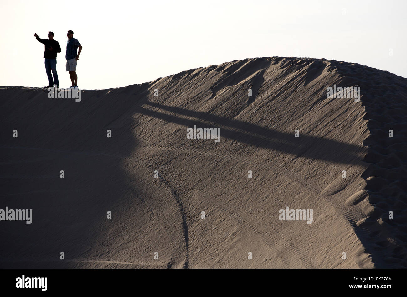 Two men in silhouette on a sand dune, Imperial Sand Dunes Recreation Area, California USA Stock Photo