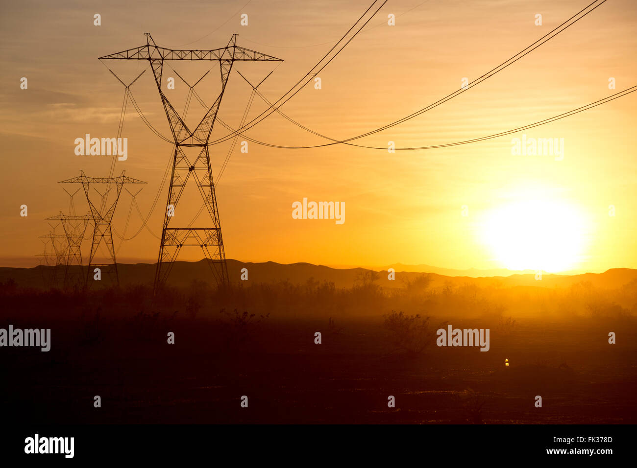 High tension power lines and the setting sun in the Sonoran Desert, California, USA Stock Photo