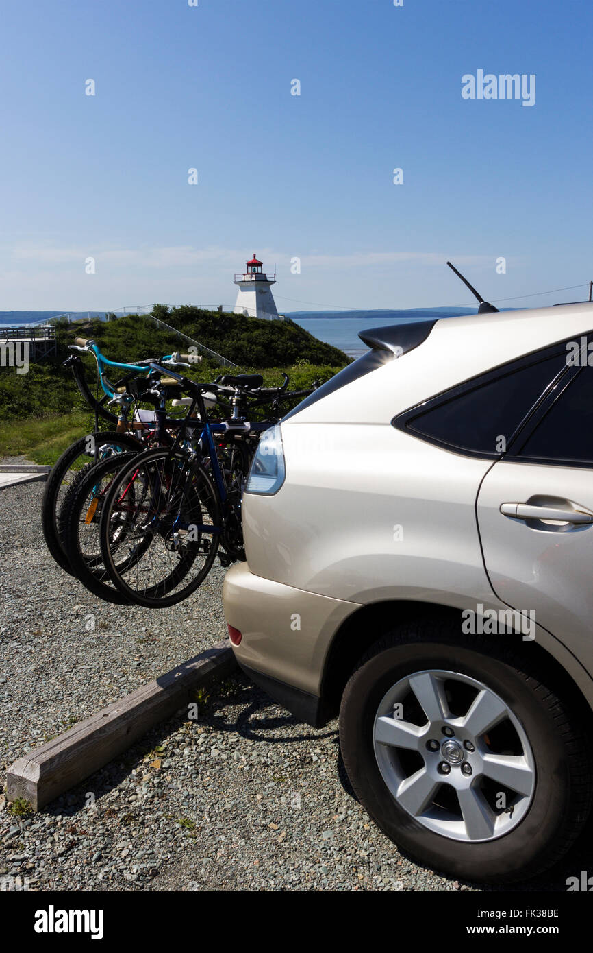 Rear mounted bike rack on a car near a lighthouse in New Brunswick in