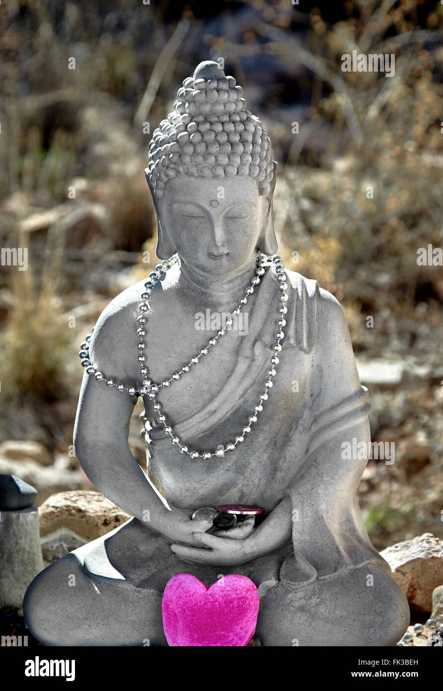 Cement statue of Buddha in lotus position with prayer beads and