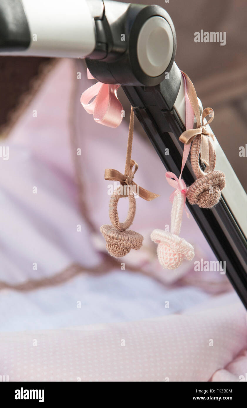 Decorative crochet pacifiers hanging on  stroller bar Stock Photo