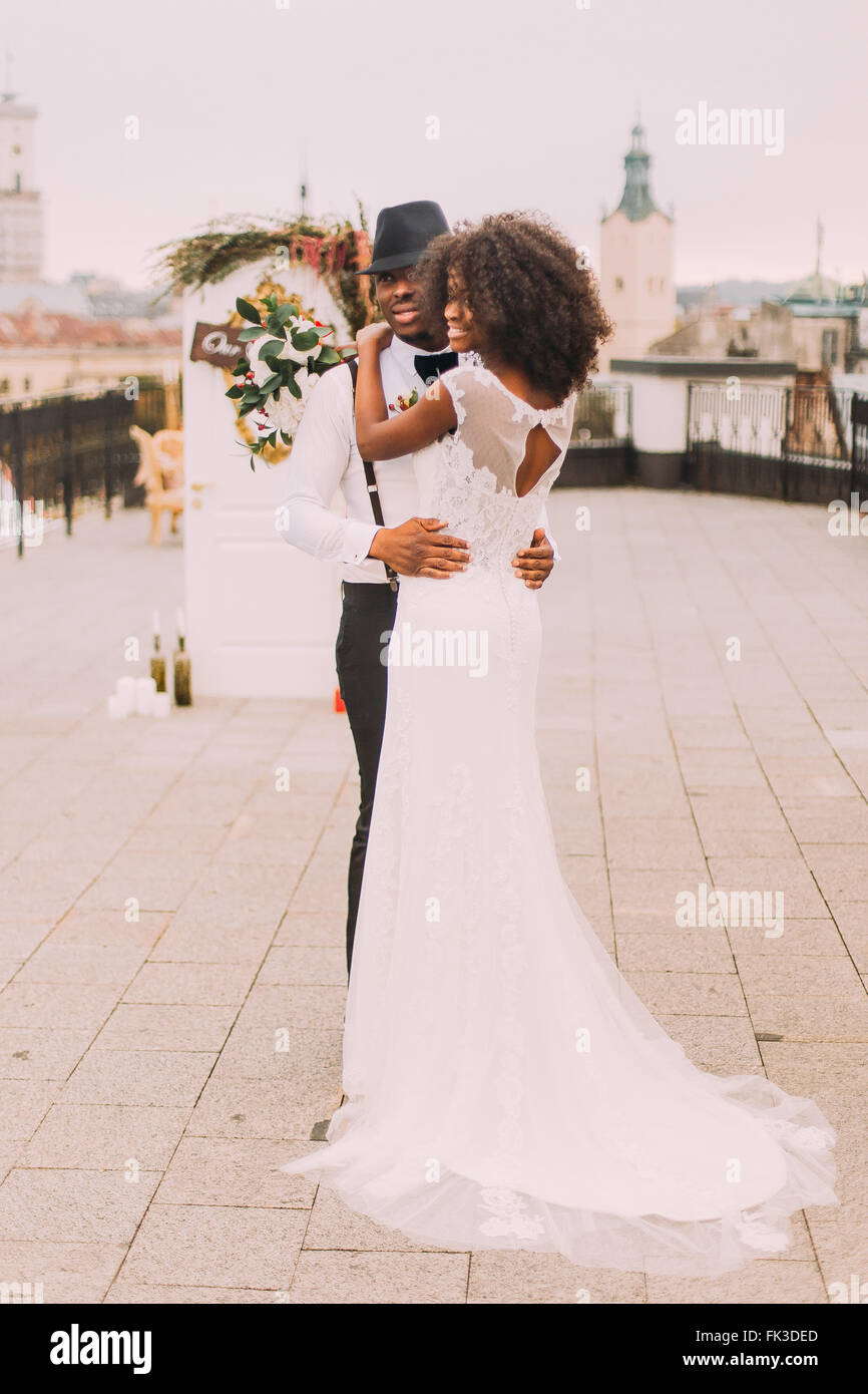 african bride in white lace wedding dress happy in the arms of
