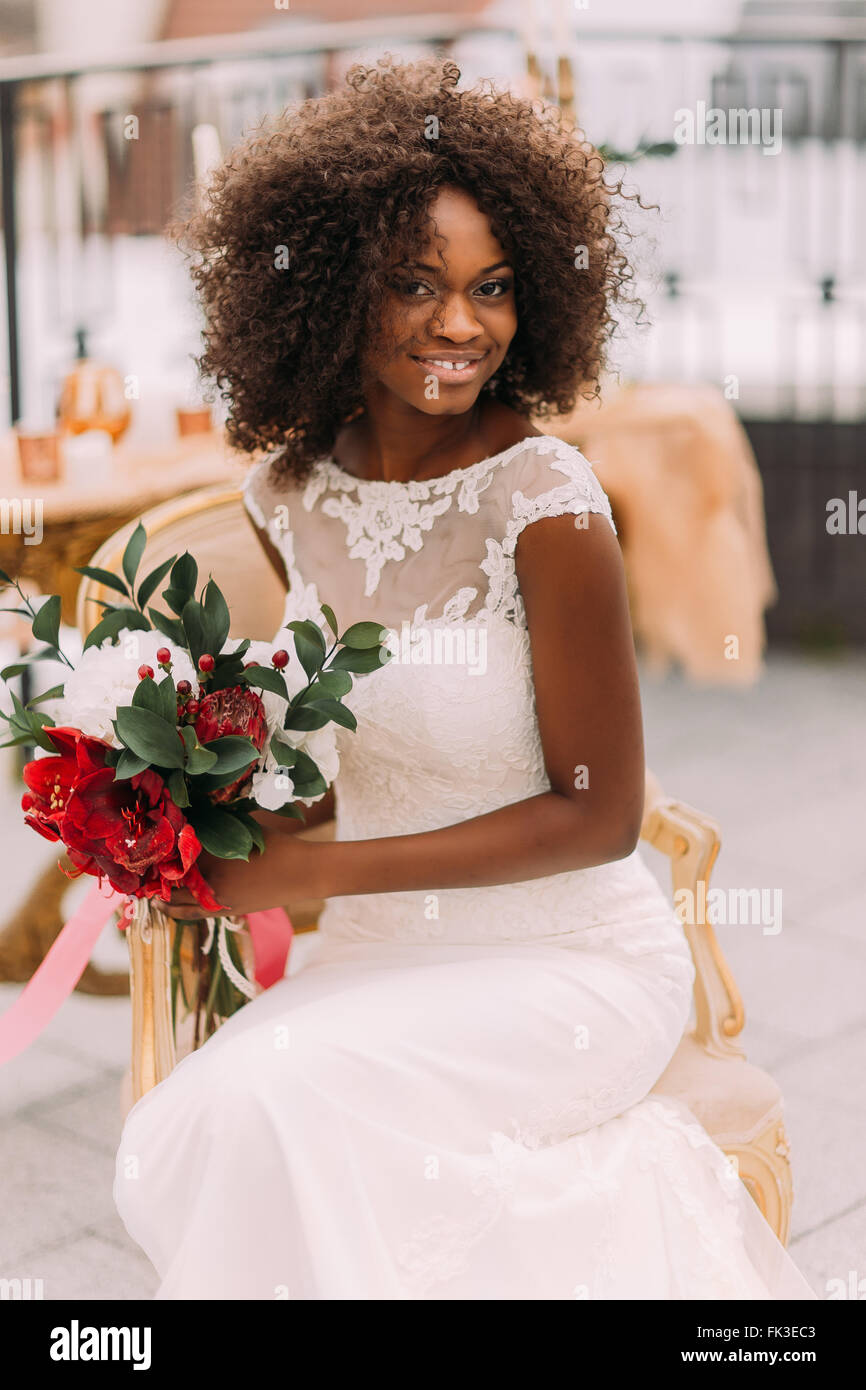 Charming african bride with wedding bouquet in hands cheerfully smiling to the camera Stock Photo