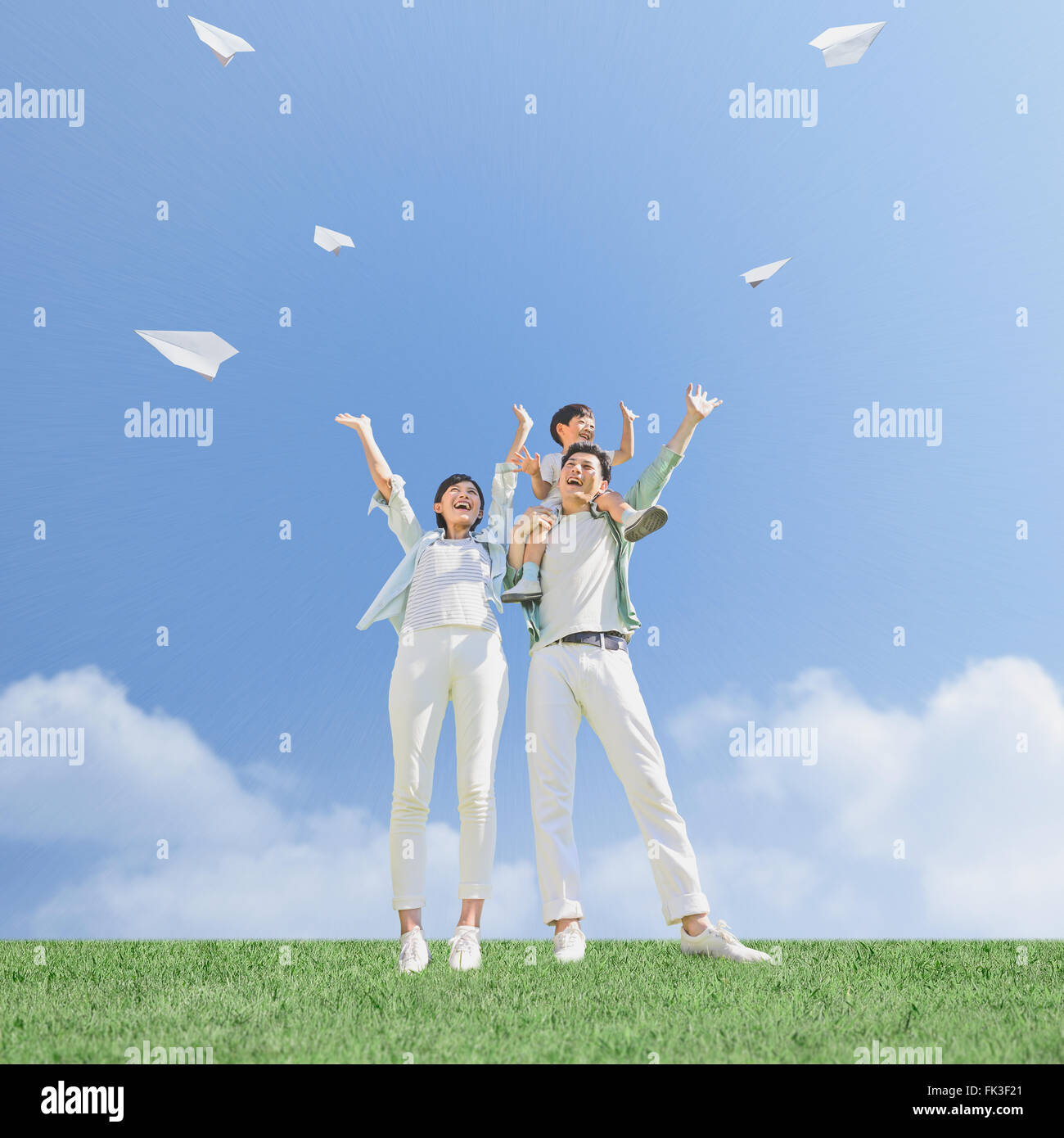 Japanese family flying paper planes in a city park Stock Photo