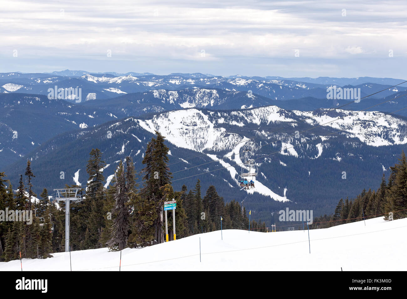 Snowboarders riding Ski Lifts up the slope of Mount Hood Oregon with Cascade Range view in Winter Season Stock Photo