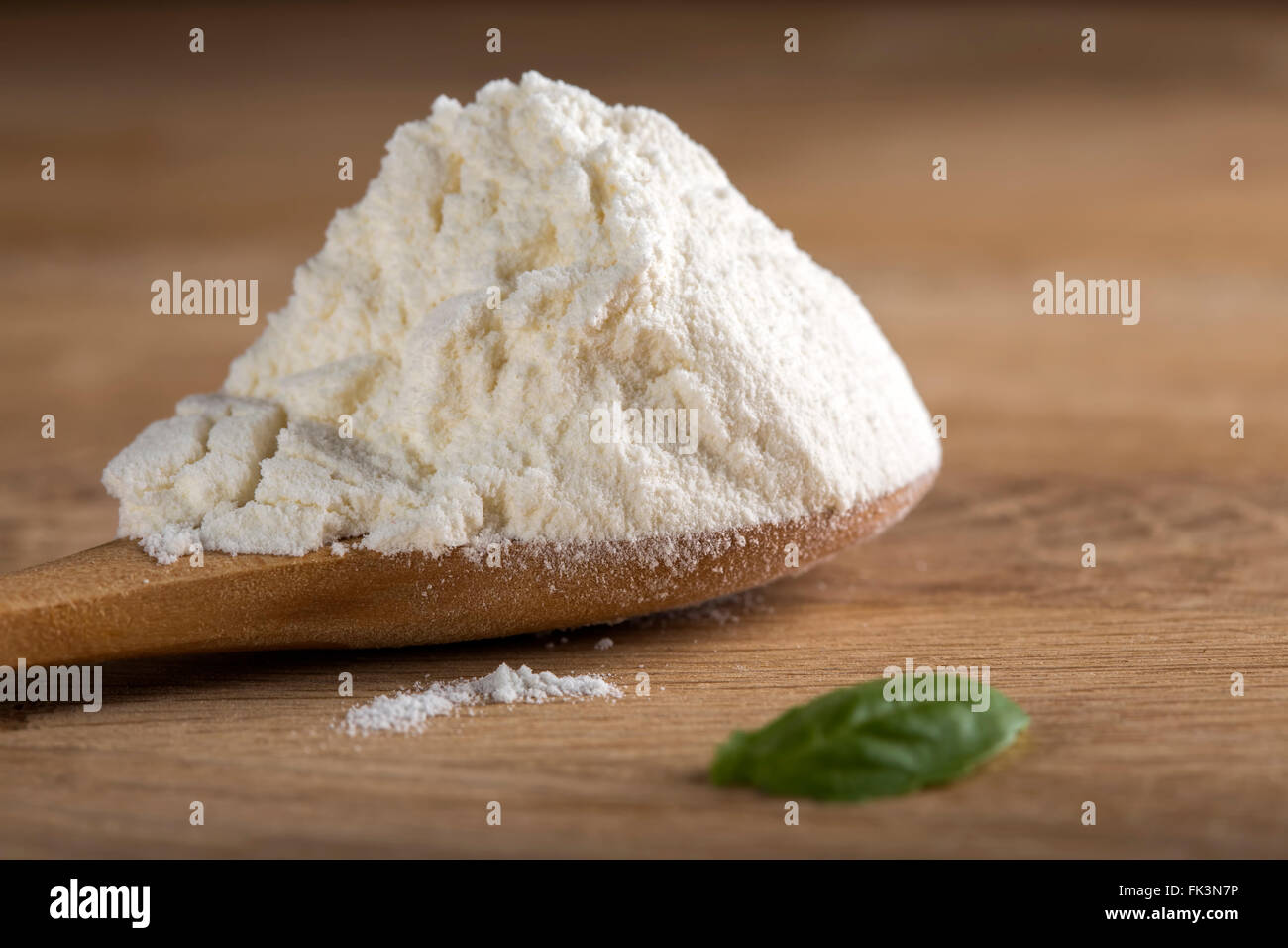 White flour in spoon on wooden background with shallow depth of field Stock Photo