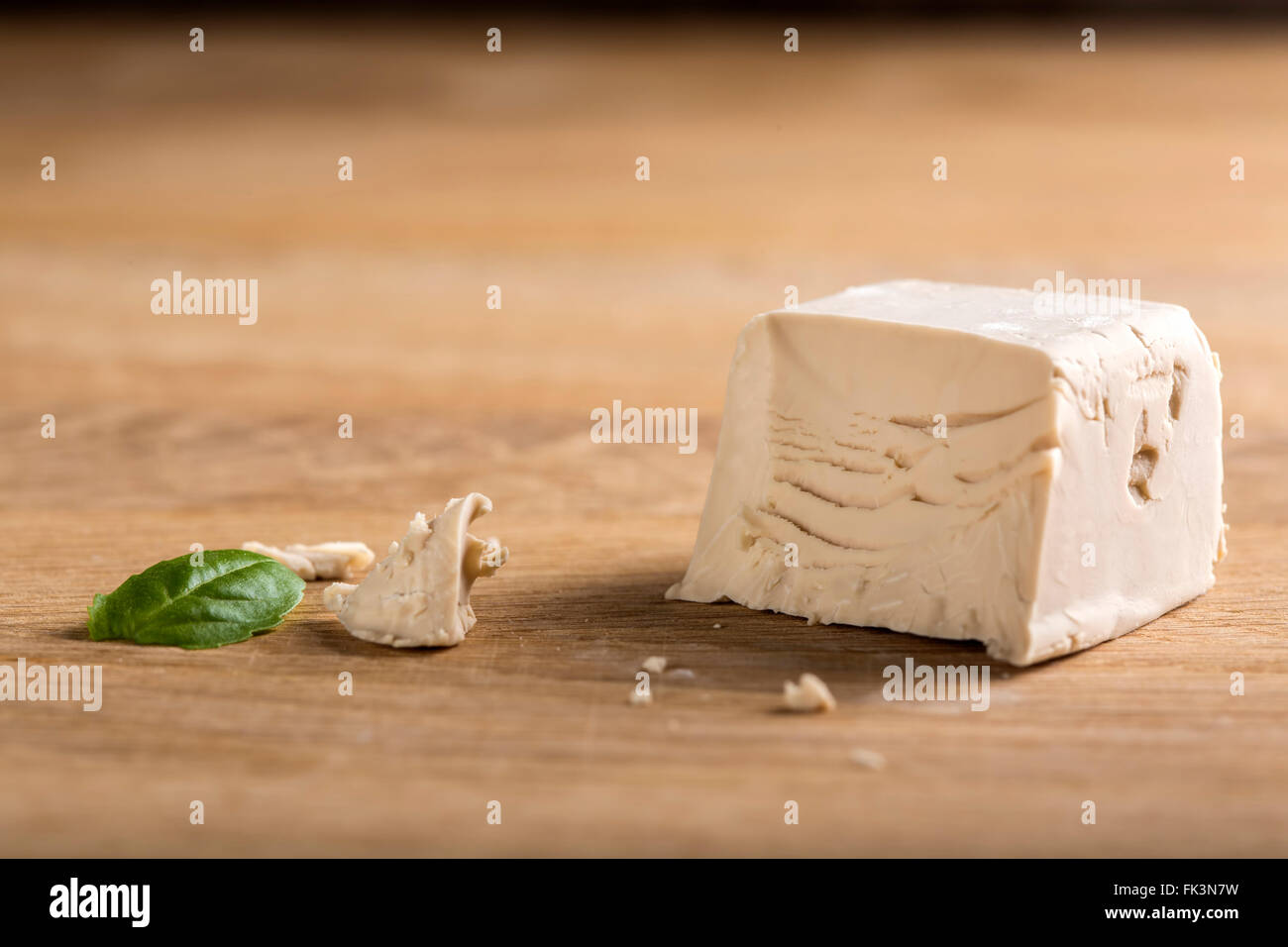Crumbled yeast cube on a wooden board Stock Photo