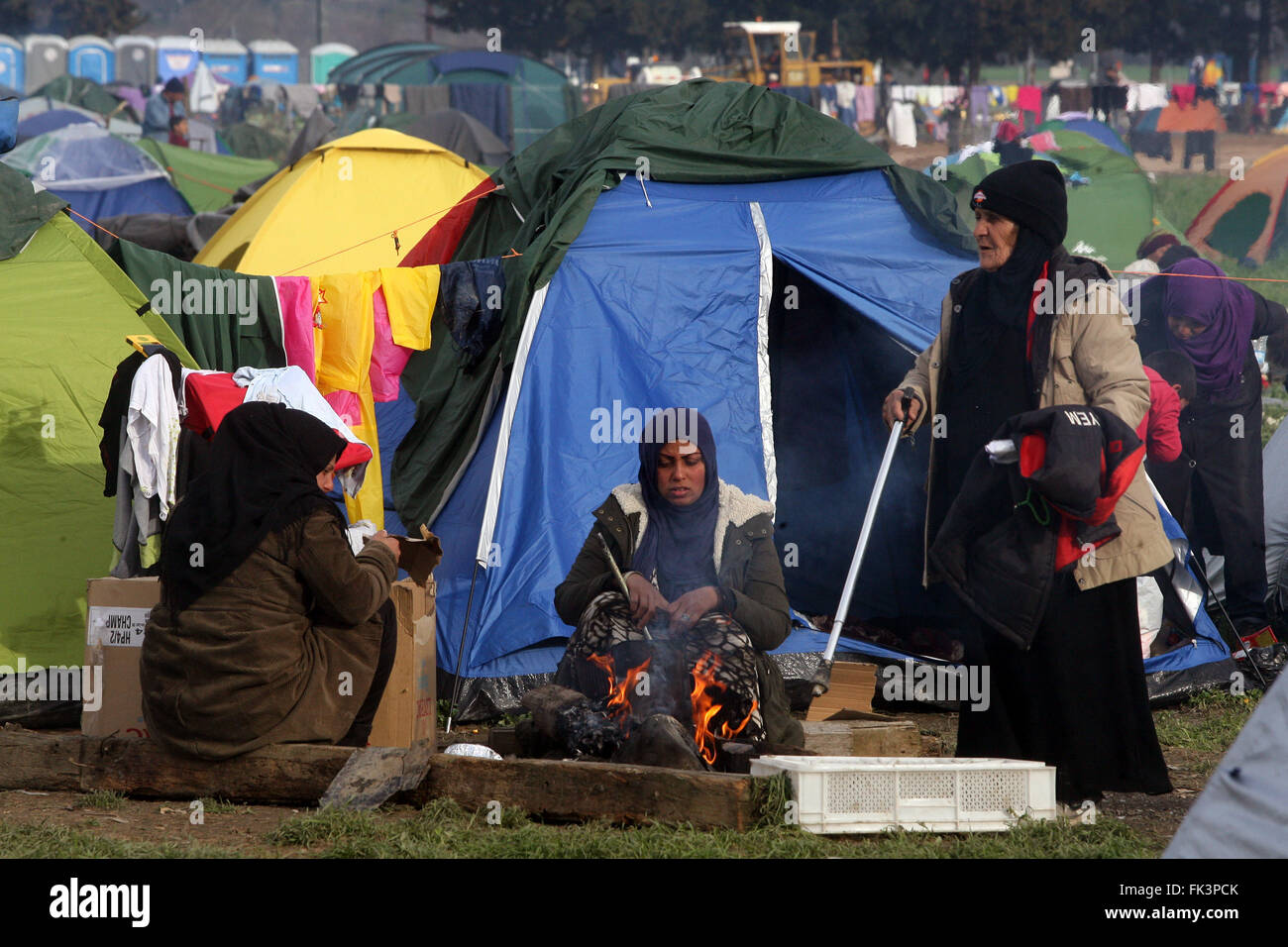 Athens. 4th Mar, 2016. Refugees warm themselves by a fire at Greece ...