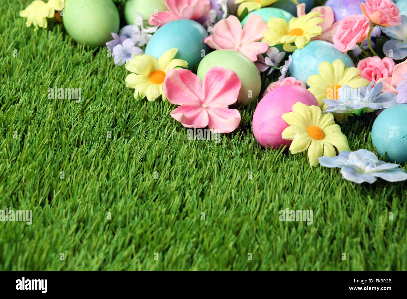 Colorful Easter eggs on grass with flowers background Stock Photo - Alamy