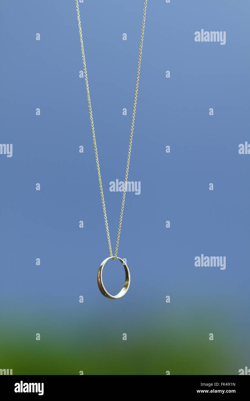 A wedding ring dangling on a chain. Stock Photo