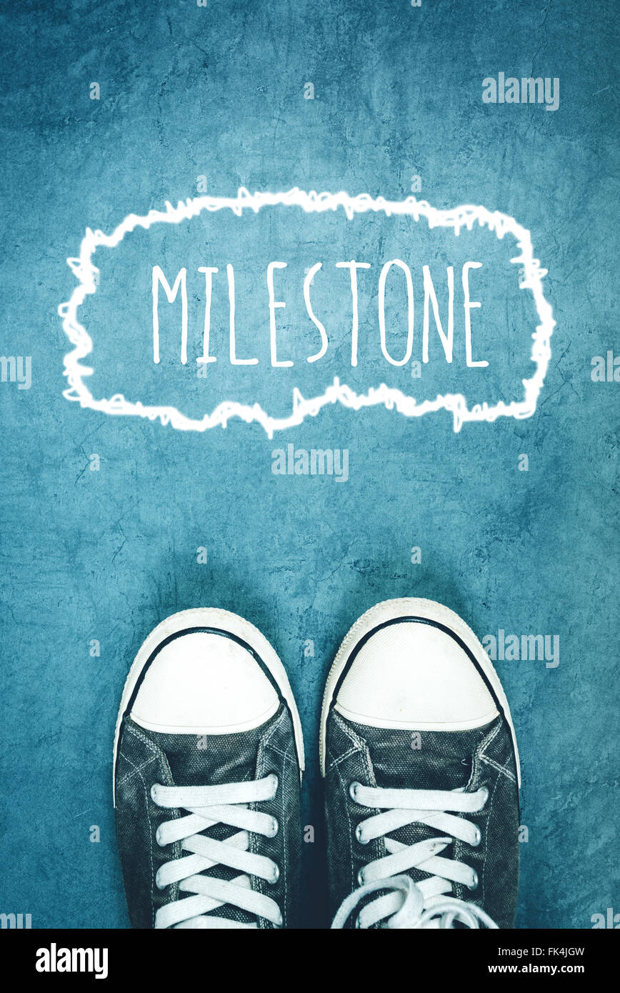 Young man standing on the street, milestone marking on road, concept of breakthrough achievement Stock Photo