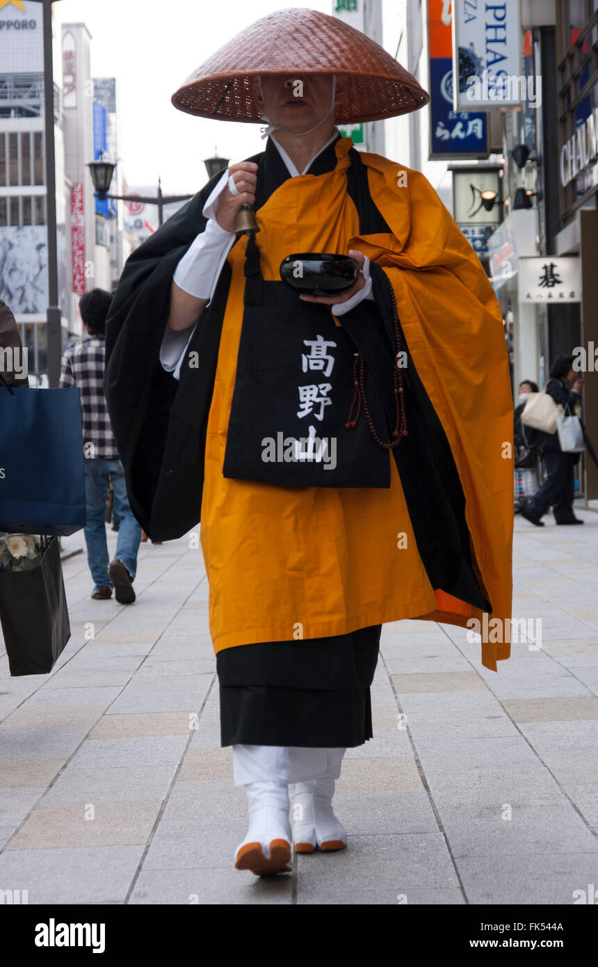 Japan Tokyo Ginza shinto monk in traditional dress walking on pavement collecting donations Stock Photo
