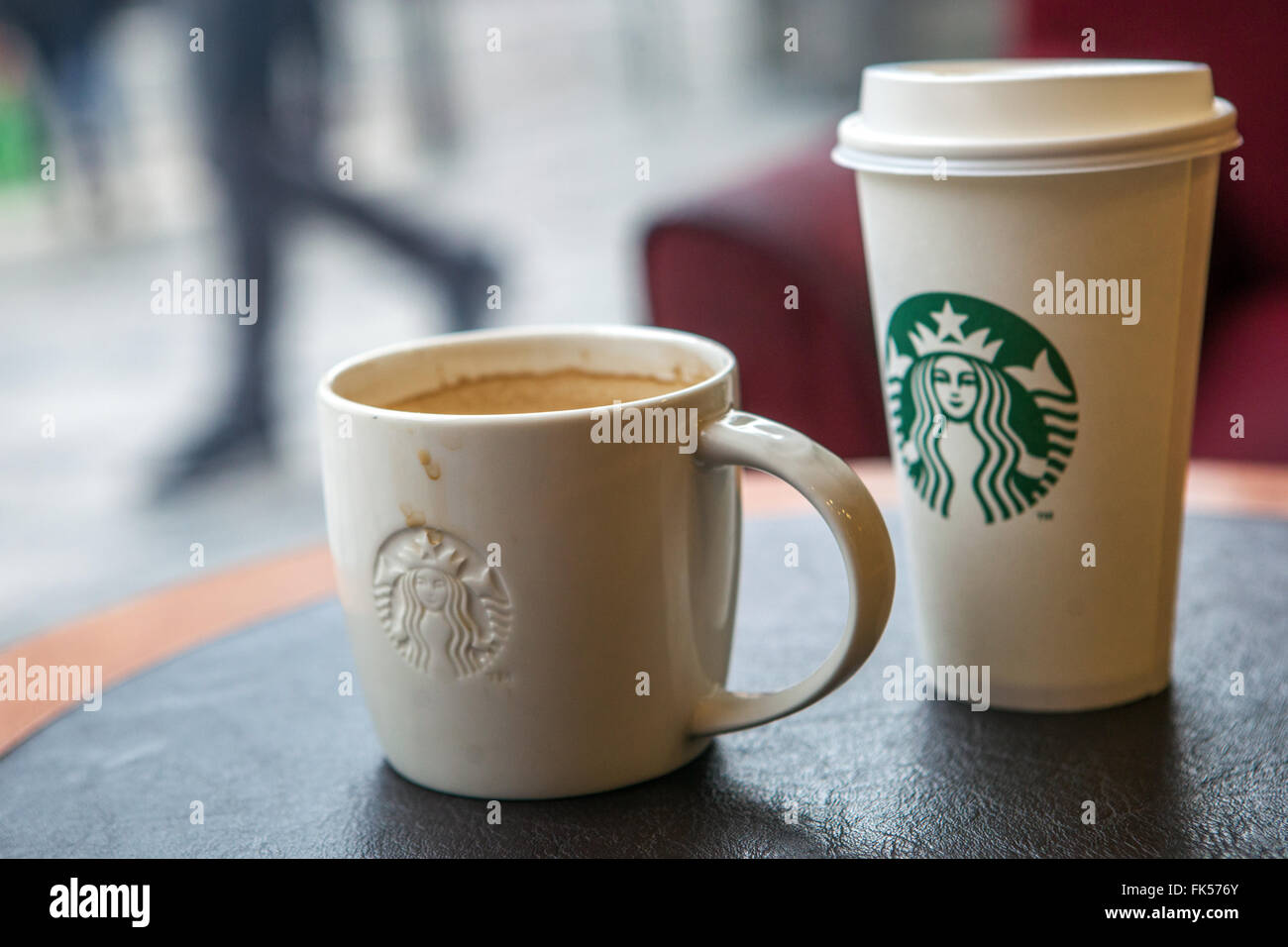 Starbucks coffee cups on a table and the street outside the window Stock Photo