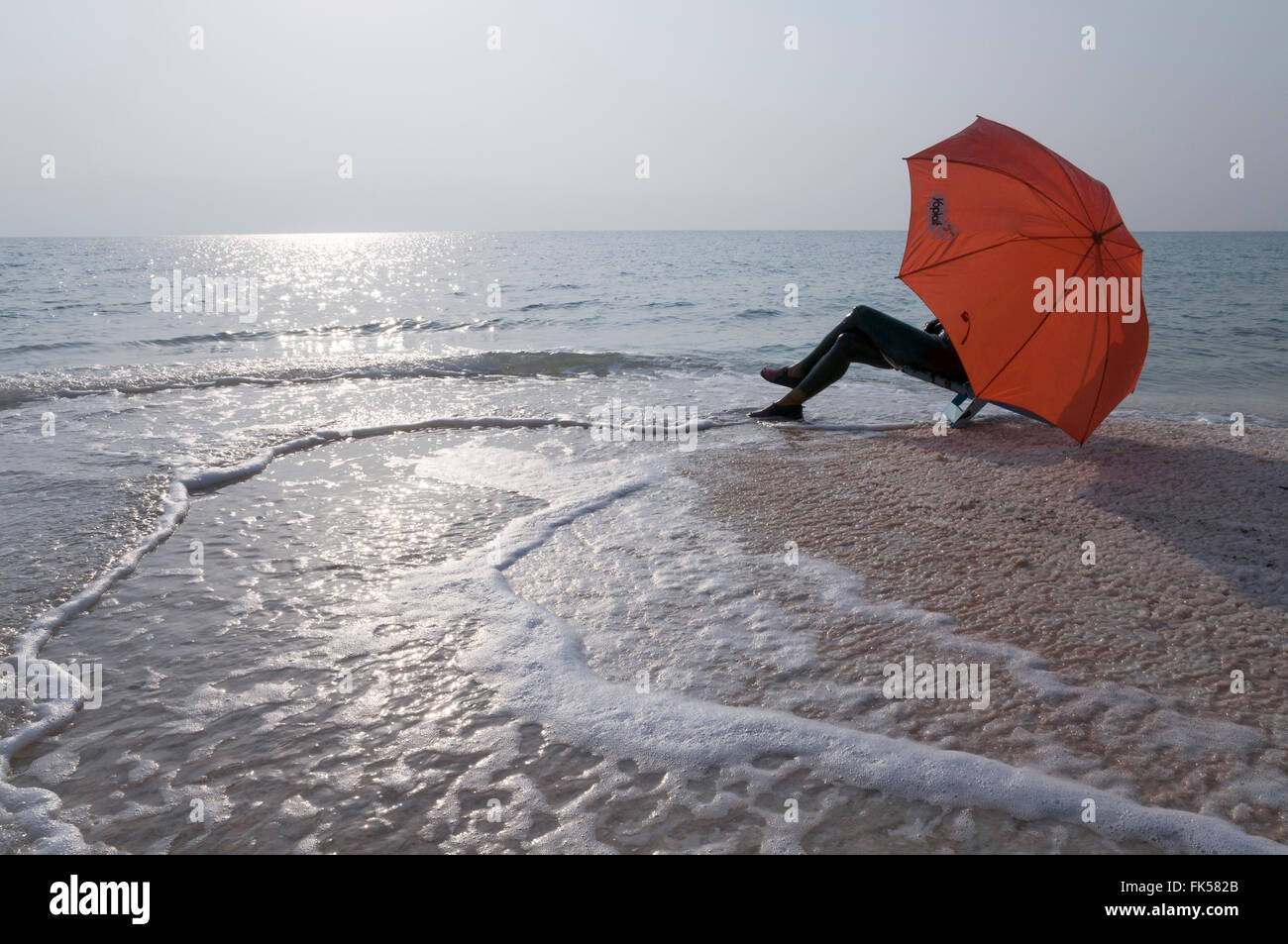 woman with umbrella sunbathing at the Dead Sea. Israel Stock Photo
