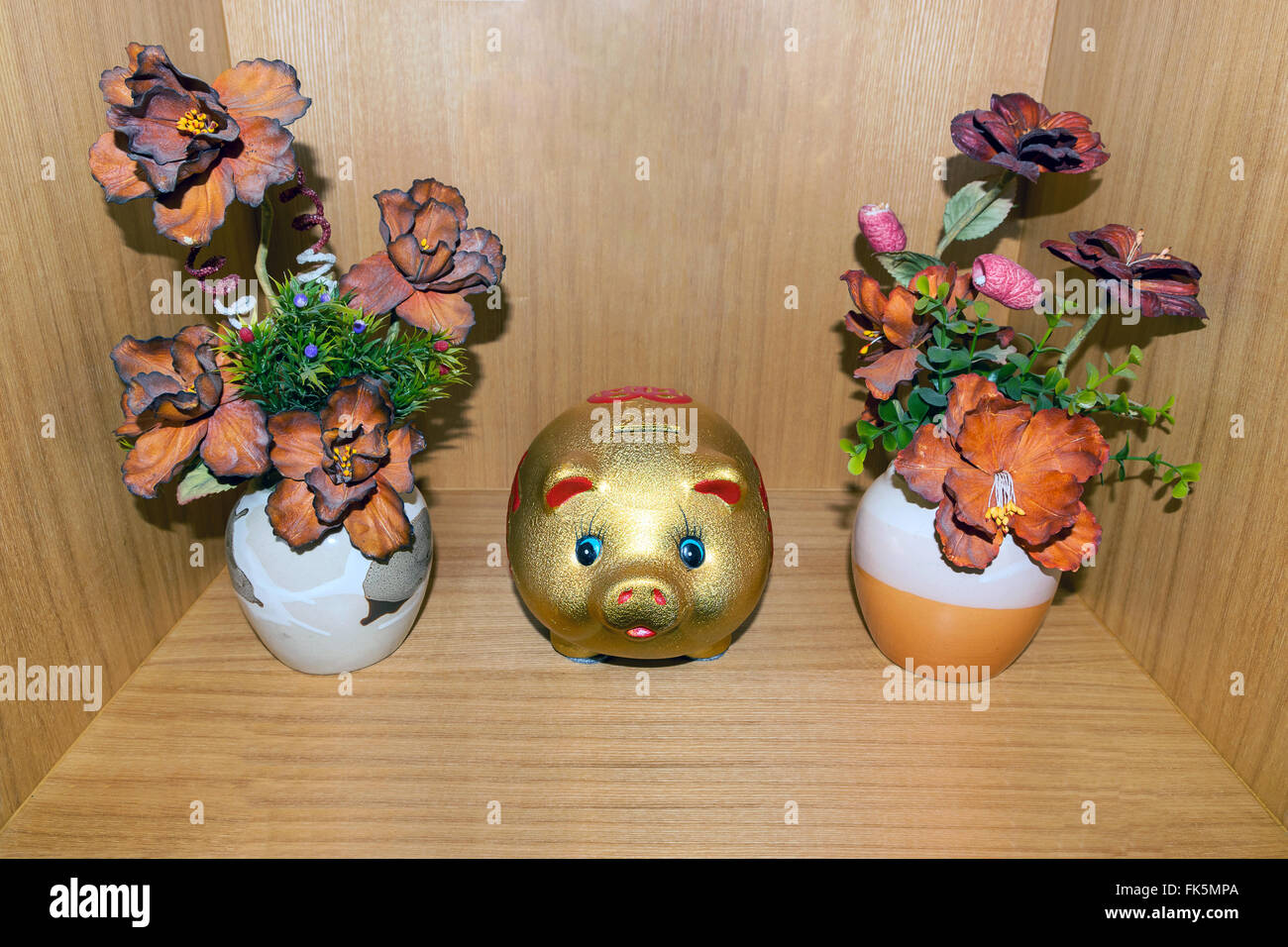 Vase plastic flower and piggy bank on wood background. Stock Photo