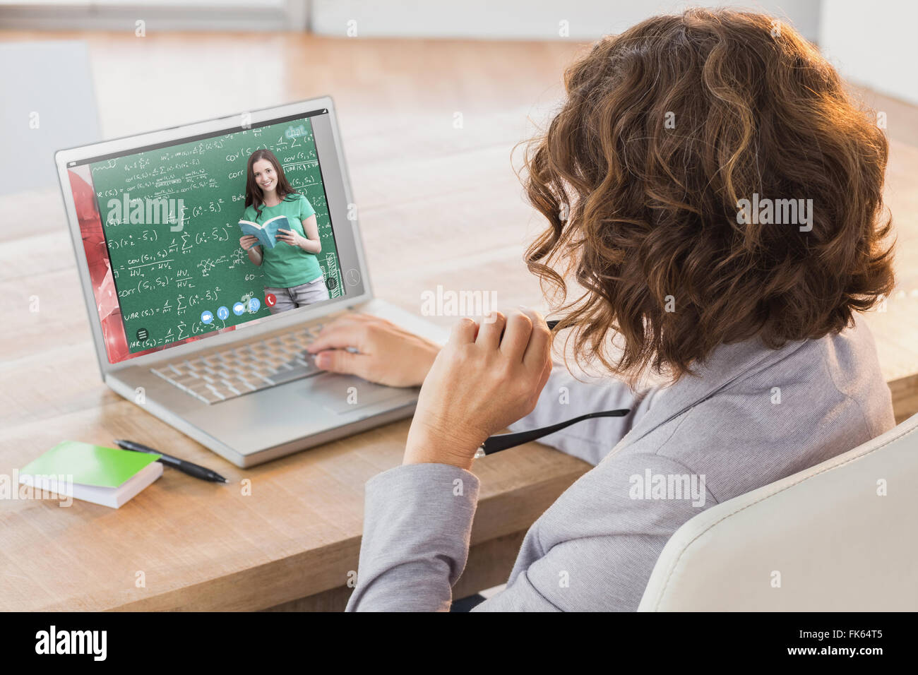 Composite image of businesswoman using laptop at desk in creative office Stock Photo