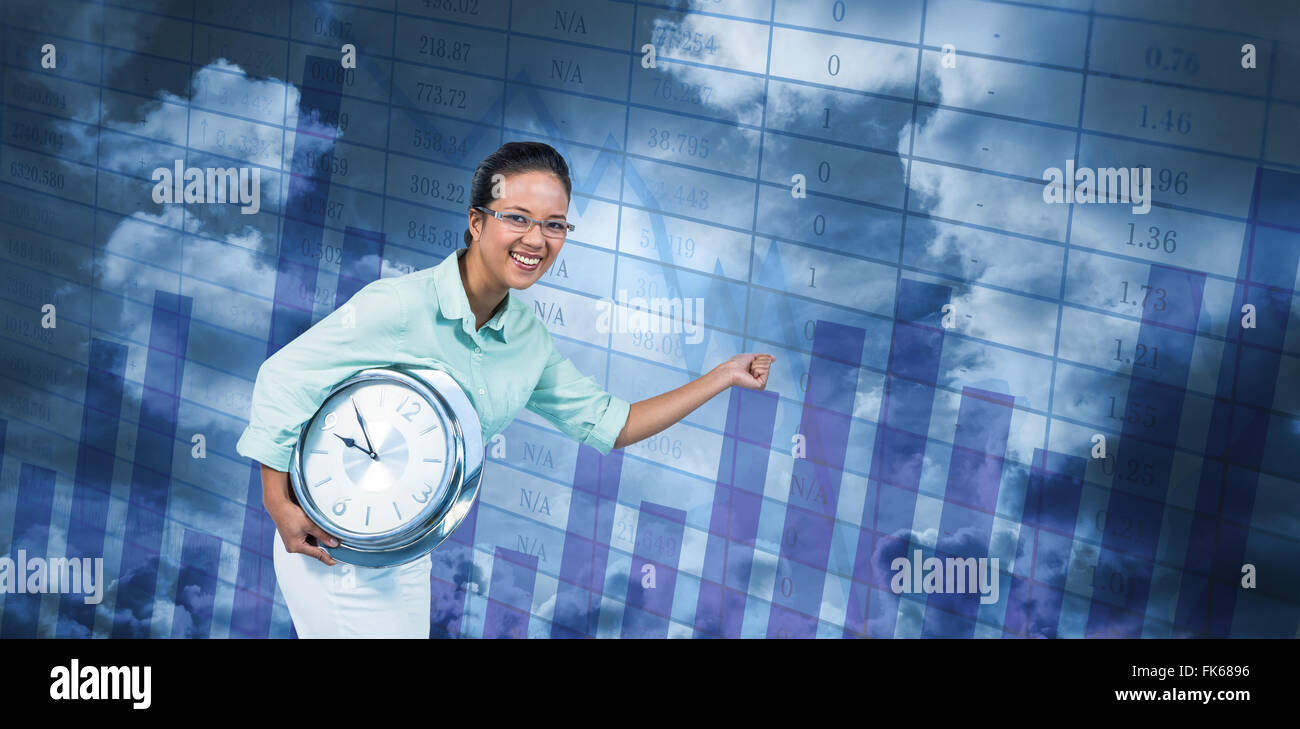 Composite image of delighted businesswoman holding a clock Stock Photo