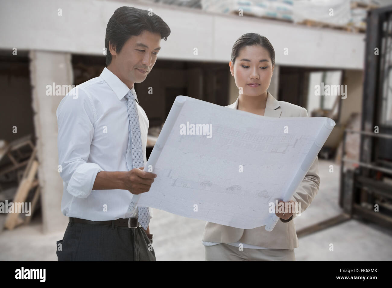 Composite image of estate agent and buyer looking at blueprint Stock Photo