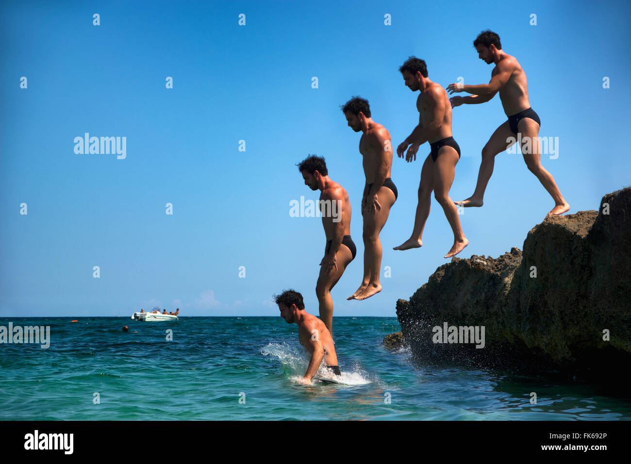 Man jumping from cliff in water. Summertime. Stock Photo