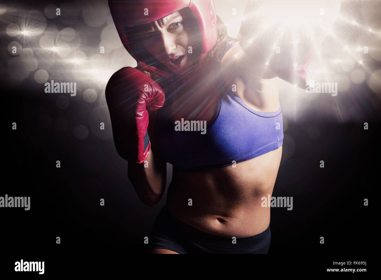Composite image of female boxer with gloves and headgear punching Stock Photo