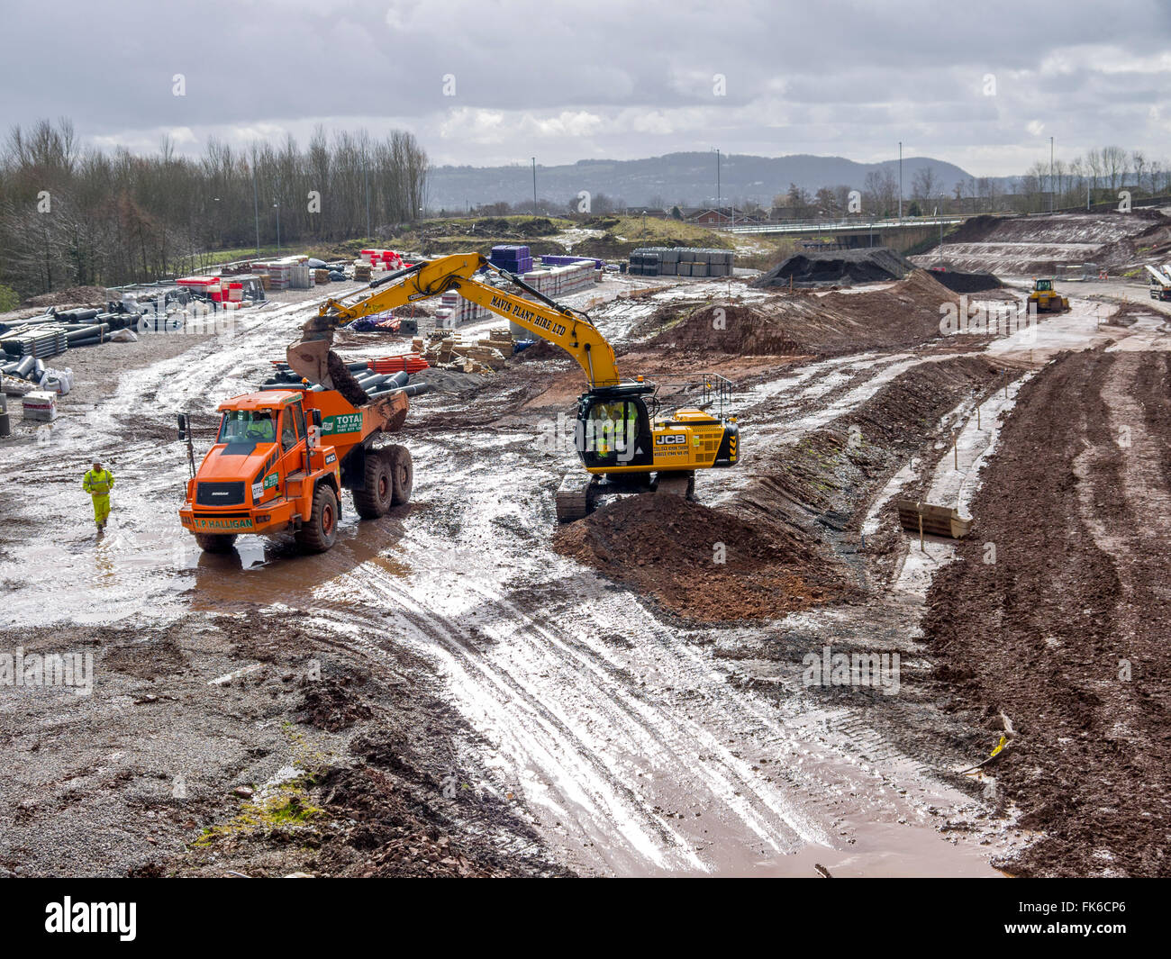 Digger loading soil in to a dump truck, very muddy and wet looking ...