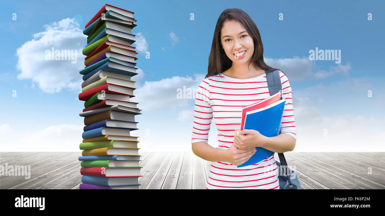 Composite image of college girl holding books with blurred students in ...