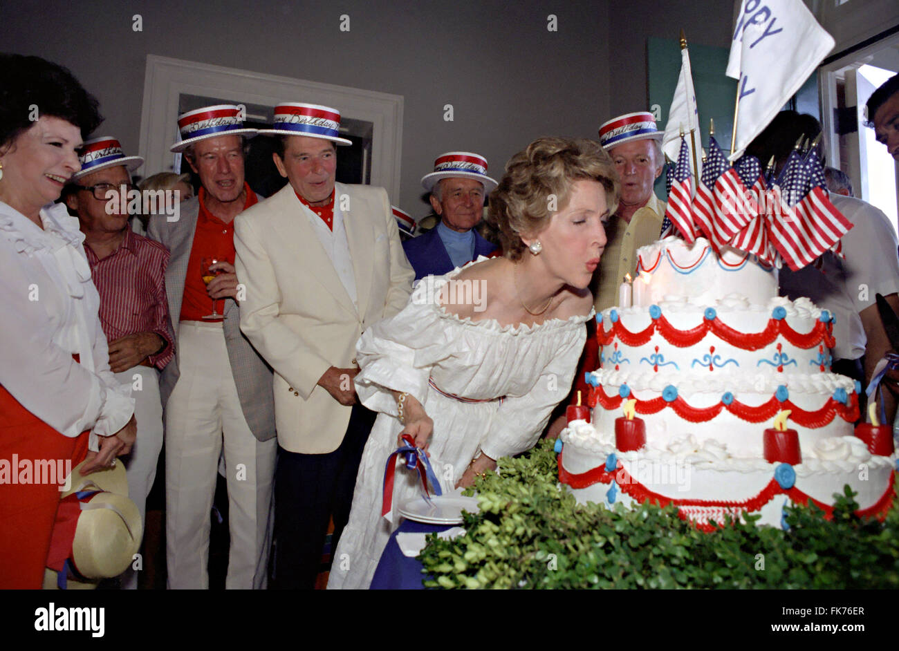 First Lady Nancy Reagan blowing out birthday candles during a party to celebrate Independence Day as President Ronald Reagan, Earle Jorgensen and William Wilson look on at Woodlawn Plantation July 4, 1981 in Mount Vernon Virginia. Stock Photo