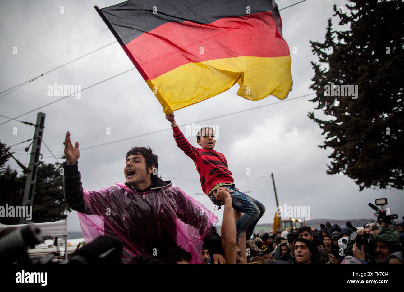 Idomeni, Greece. 7th Mar, 2016. Refugee children waving a German flag and yelling 'Mama Merkel' at the Greek-Macedonian border in Idomeni, Greece, 7 March 2016. Each day, only a few refugees from Syria and Iraq are allowed to cross the border. PHOTO: KAY NIETFELD/dpa/Alamy Live News Stock Photo