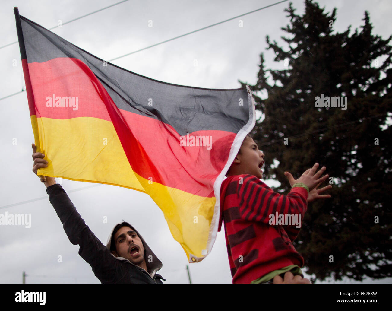 Idomeni, Greece. 7th Mar, 2016. Refugee children waving a German flag and yelling 'Mama Merkel' at the Greek-Macedonian border in Idomeni, Greece, 7 March 2016. Each day, only a few refugees from Syria and Iraq are allowed to cross the border. PHOTO: KAY NIETFELD/dpa/Alamy Live News Stock Photo