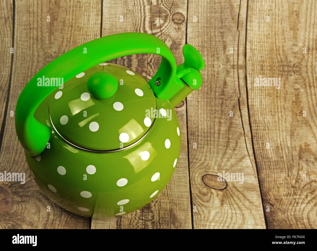 Metal, traditional kettle with a double bottom, water, whistle, green with white dots on a wooden countertop.Horizontal view on Stock Photo