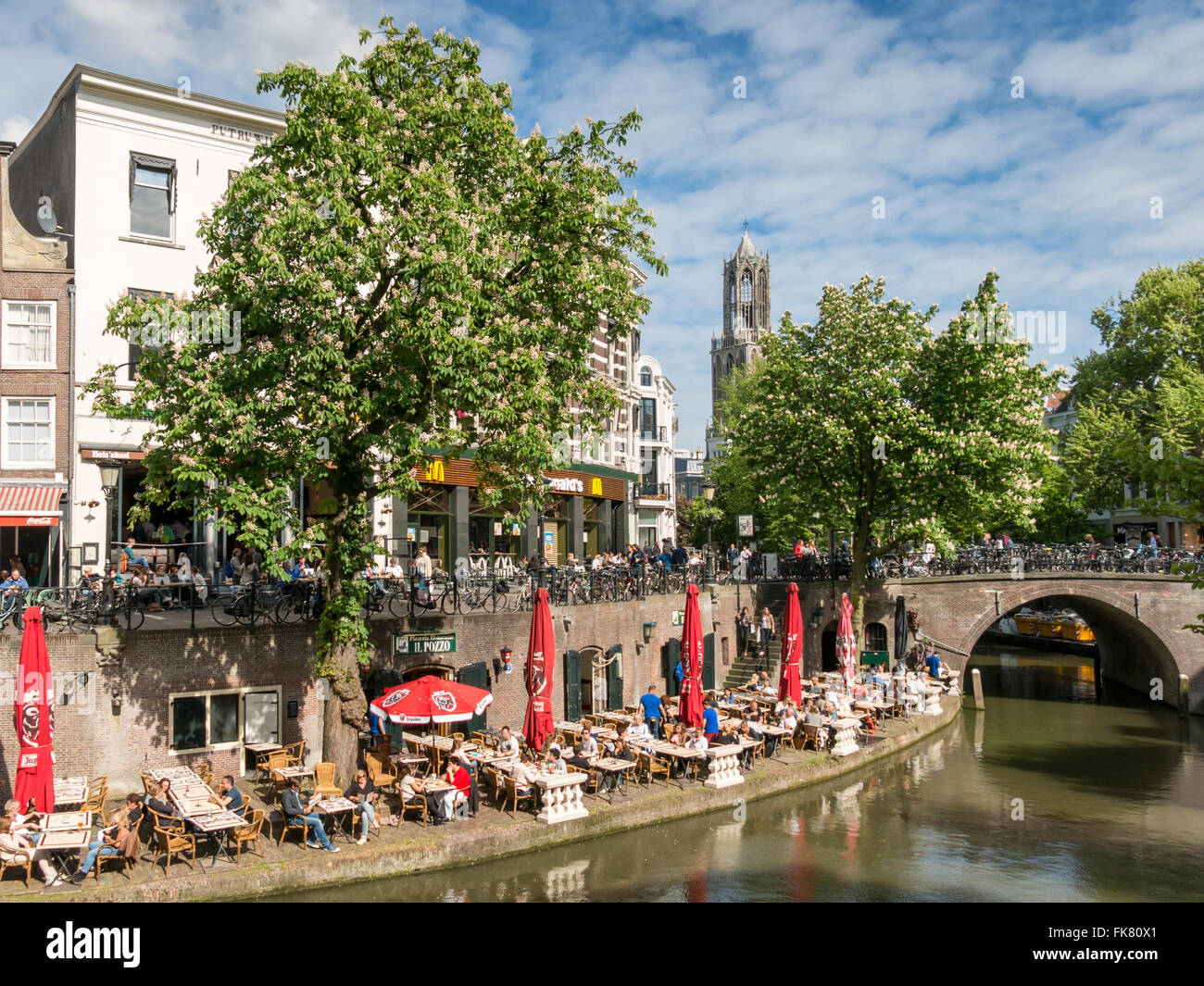 Dom Tower and people on outdoor terrace of restaurant along Oudegracht canal in the old city centre of Utrecht, Netherlands Stock Photo