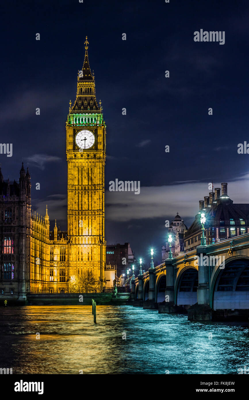 The beautiful Elizabeth Tower with the bells of Big Ben on top and the parliament near a bridge above the Thames river in London at night. Stock Photo