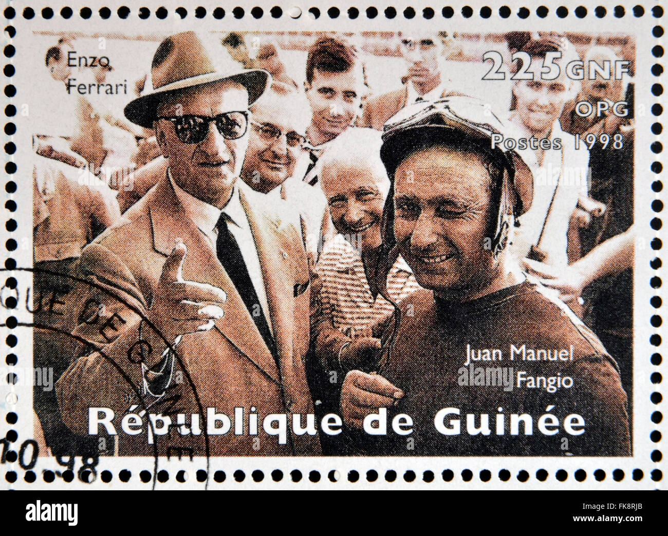 GUINEA - CIRCA 1998: Stamp printed in Guinea dedicated to anniversary of Enzo Ferrari, shows Enzo Ferrari and Jose Manuel Fangio Stock Photo