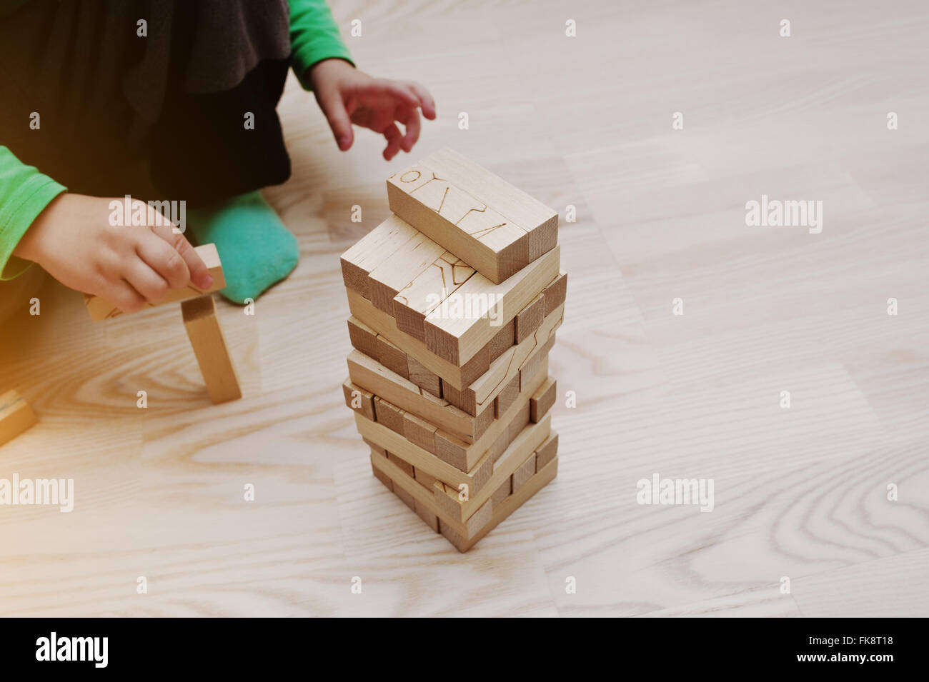 Hand of baby who played developmental game of wooden blocks lumber