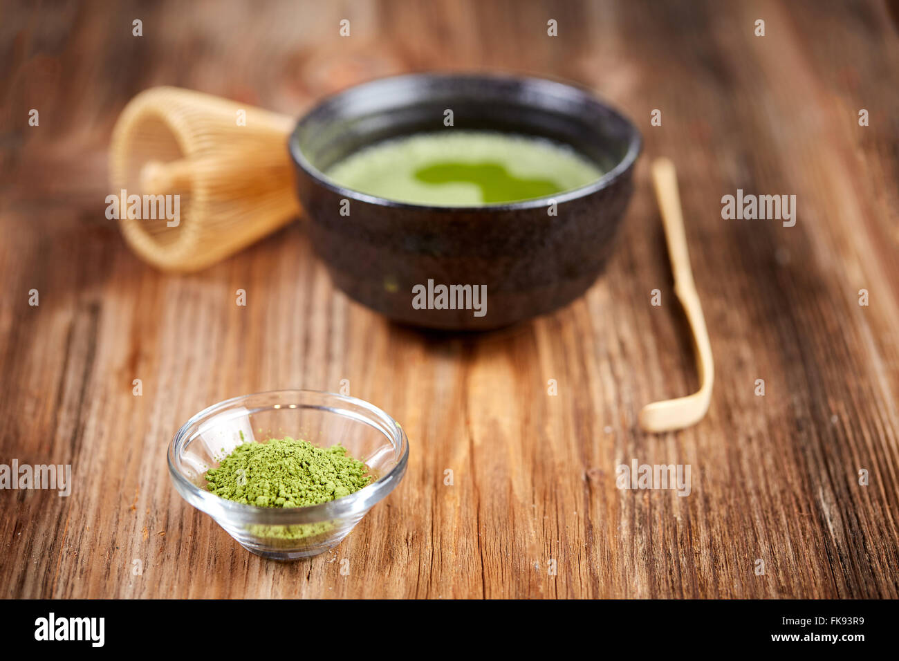 Green matcha tea and powder, whisk and spoon on a wooden table Stock Photo