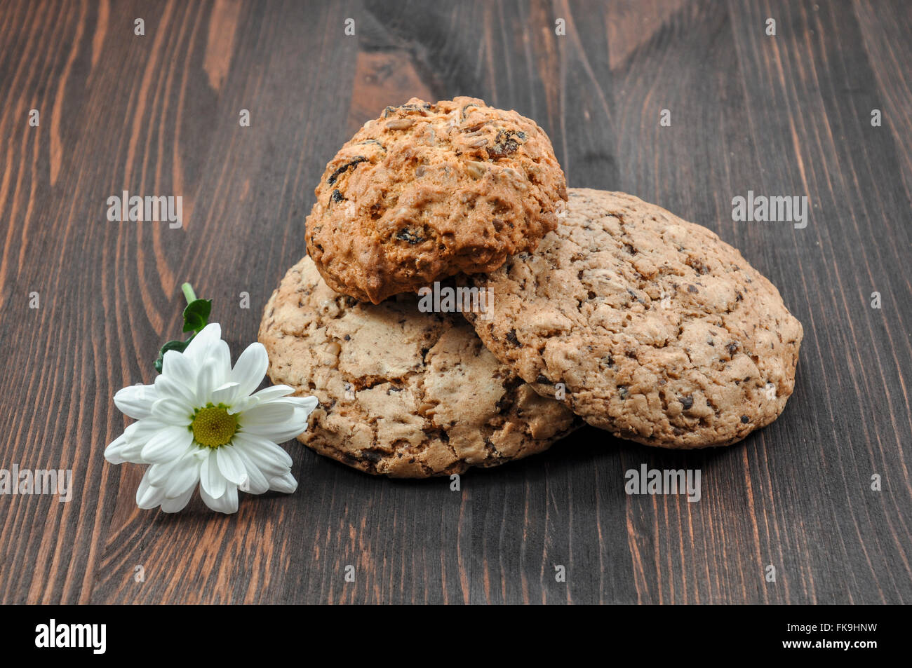 two chocolate cookies with a flower on a wooden background Stock Photo