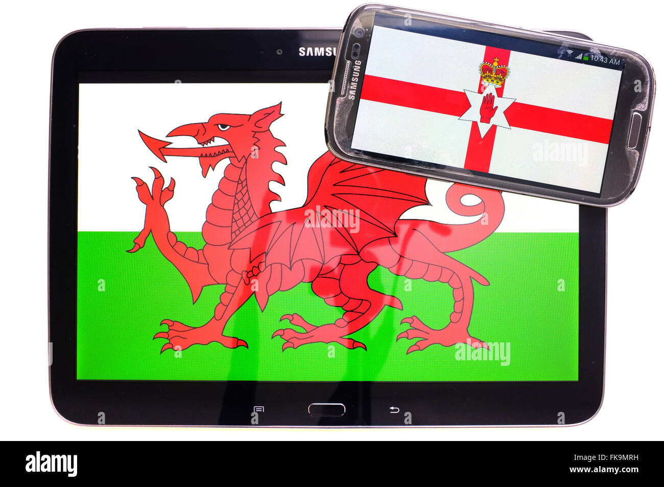 A tablet with the Welsh flag on it and a smartphone with the Northern Irish flag photographed against a white background. Stock Photo