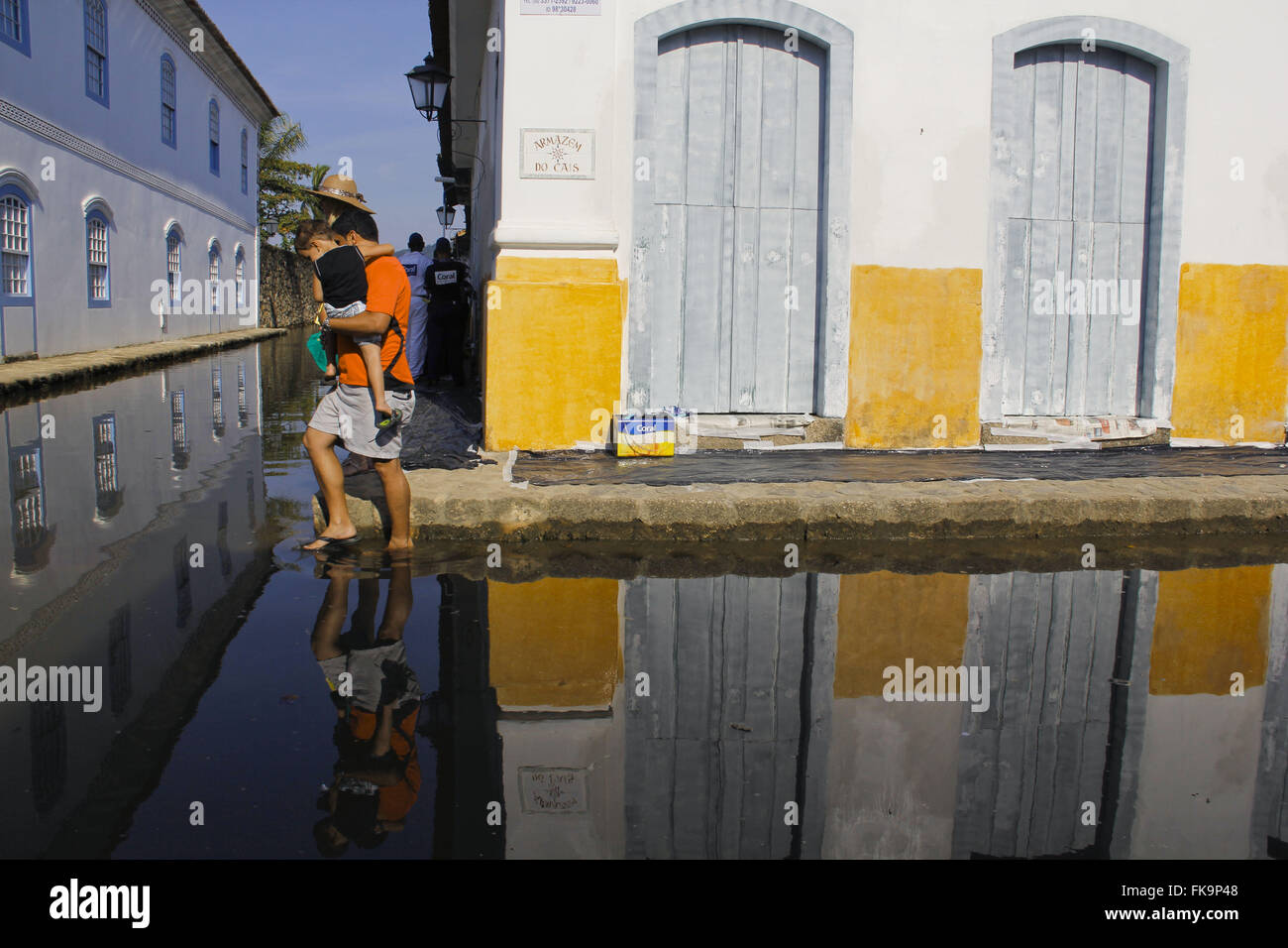 Man holding child in flooded street in the historic center of Paraty - RJ Stock Photo