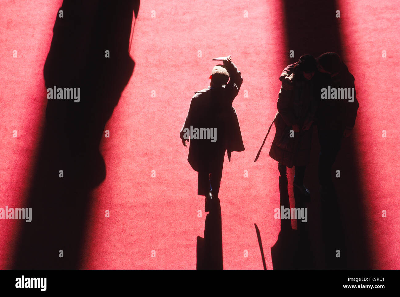 View above visitors casting long winter shadows on red carpet Stock Photo