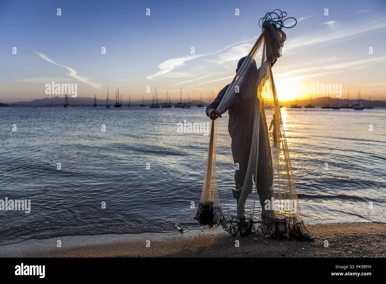 Fisherman in Santo Antonio de Lisboa beach at sunset Stock Photo