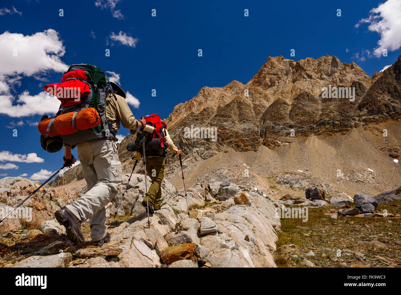 Backpackers hiking with clouds over granite in Humphreys Basin in the High Sierra outside of Bishop, CA. Stock Photo