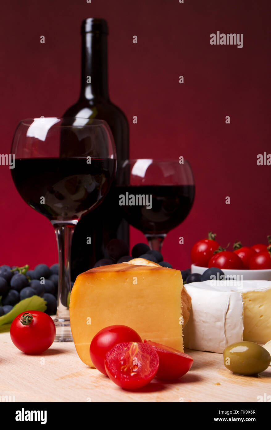 Still life with cherry tomato, red wine and cheese Stock Photo - Alamy