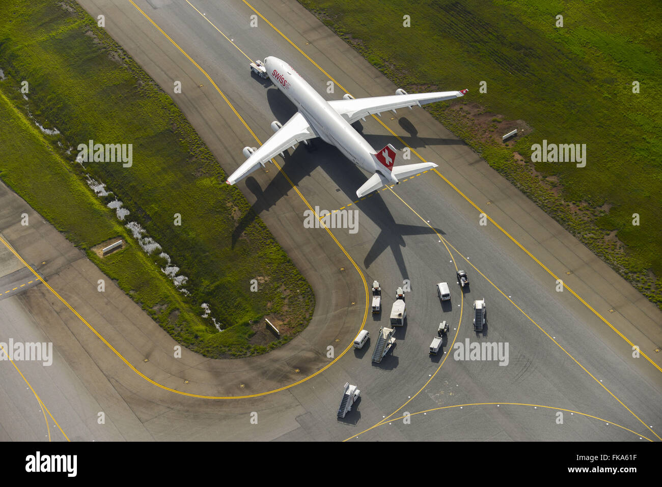 Plane being pulled by tractor and vehicle following ports Supported Stock Photo