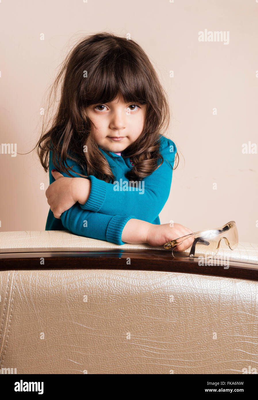 Samll girl leaning on cushion arm inside studio Stock Photo