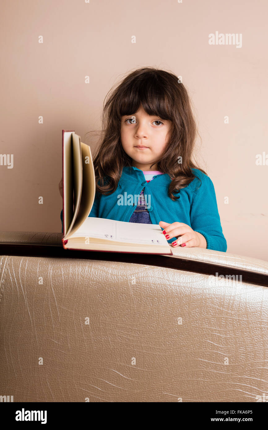 Samll girl inside studio with red copybook in hand Stock Photo
